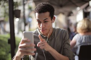 Photo of a man using a smartphone with headphones outside.